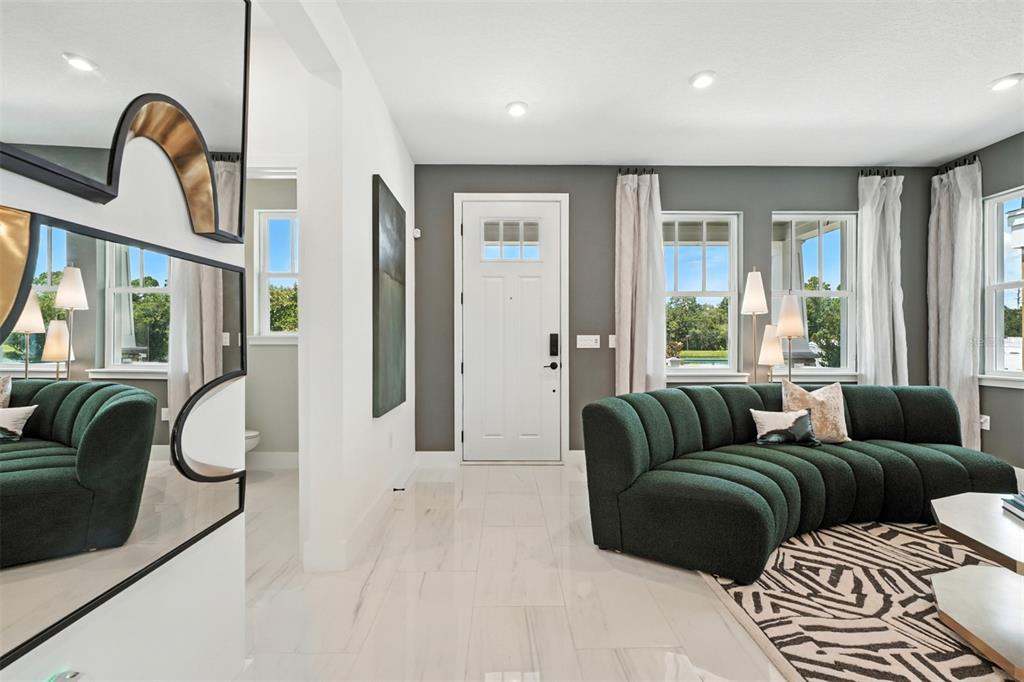 A living room features a curved green sofa, white tile floors, and a front door — 1796 HEADLAND LOOP, CELEBRATION, FL