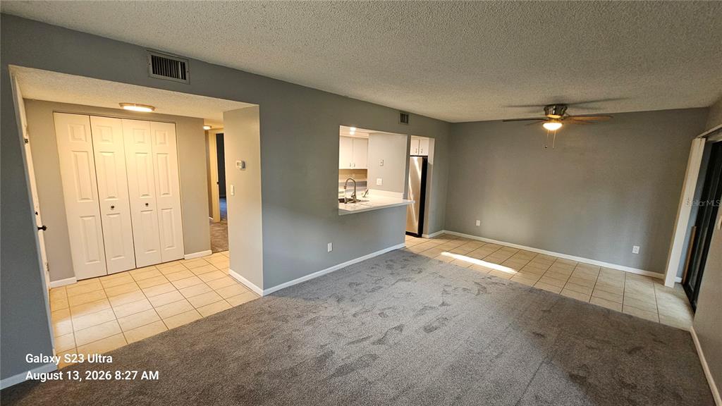 A living room with gray carpet, tile flooring, and a pass-through window to the kitchen — 7 CASTANIA COURT, ST AUGUSTINE, FL