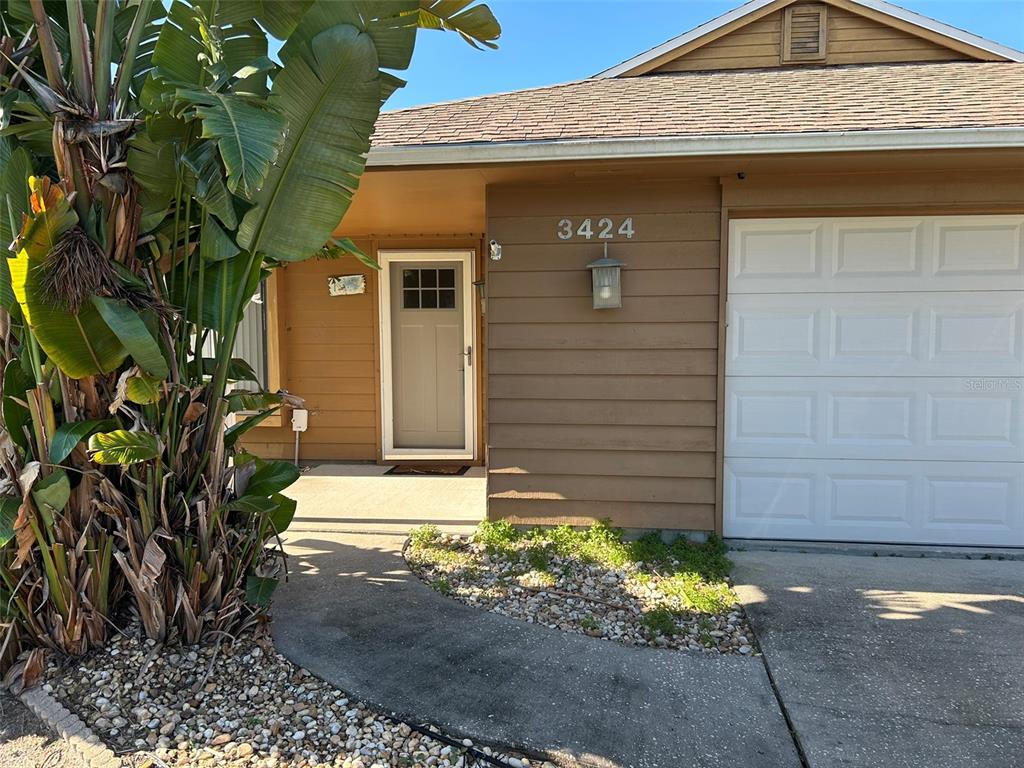 The exterior of a house features brown siding, a white garage door, and a front entrance — 3424 UNITY TREE DRIVE, EDGEWATER, FL