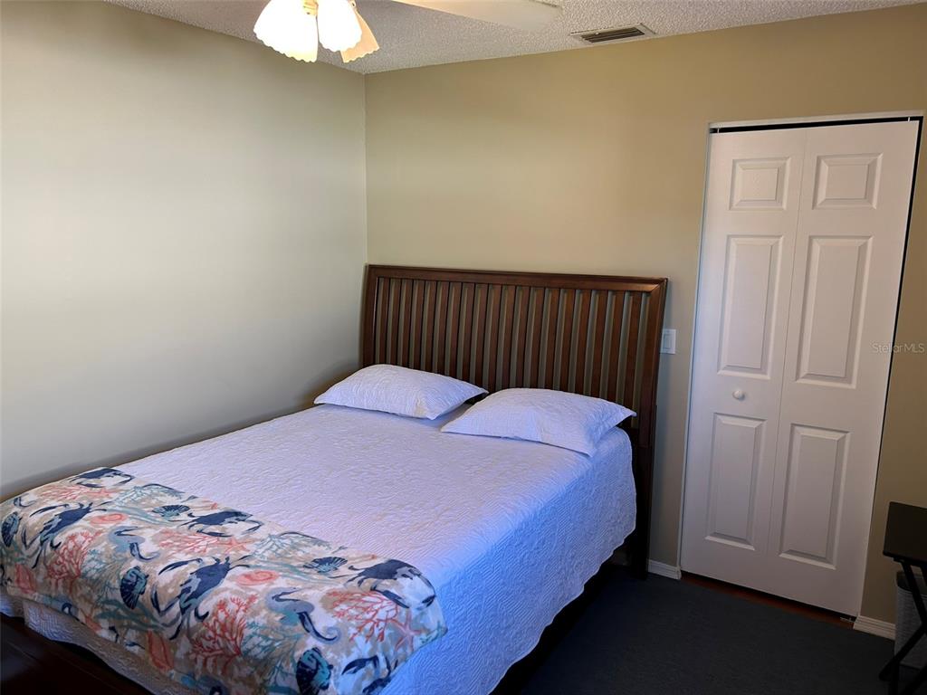 A bedroom features a bed with a wooden headboard, white bedding, and a patterned throw — 3424 UNITY TREE DRIVE, EDGEWATER, FL