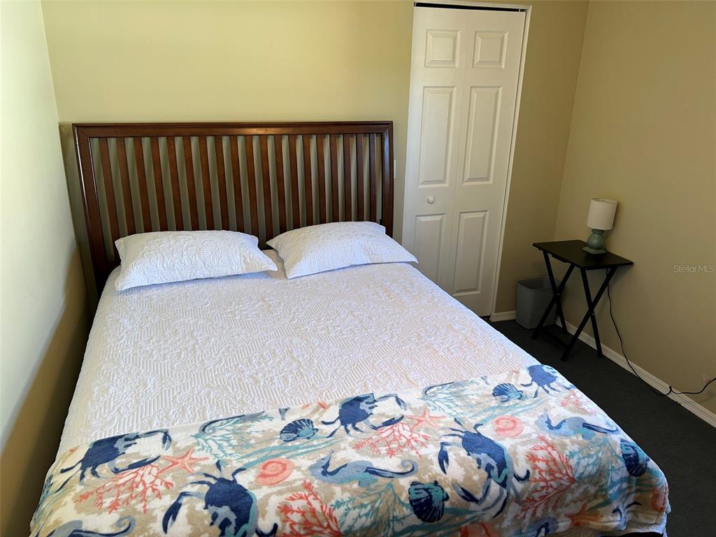 A bedroom features a wooden headboard, a white bedspread with a coastal print, and a side table — 3424 UNITY TREE DRIVE, EDGEWATER, FL