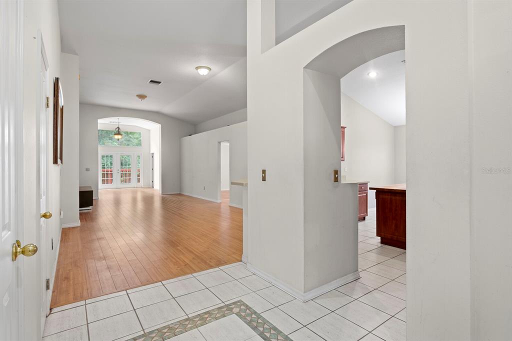 An entryway with tiled floors leads to a living area with wood flooring and arched openings — 10420 SPRINGROSE DRIVE, TAMPA, FL