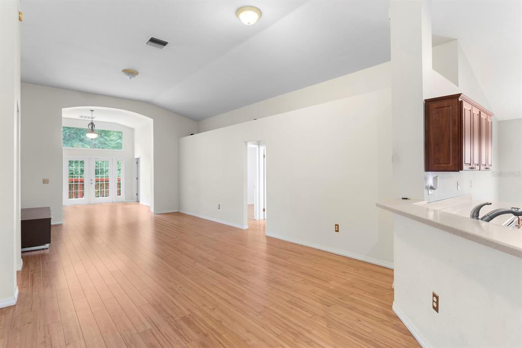 An open-concept living area with light wood flooring, a vaulted ceiling, and a kitchen counter — 10420 SPRINGROSE DRIVE, TAMPA, FL