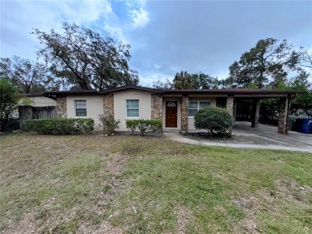 A single-story house features a stone facade, a brown front door, and an attached carport — 3011 E FLORA STREET, TAMPA, FL