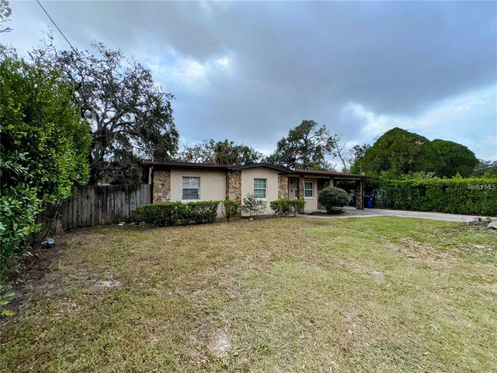 A single-story house with a stone facade, a front porch, and a large grassy yard — 3011 E FLORA STREET, TAMPA, FL