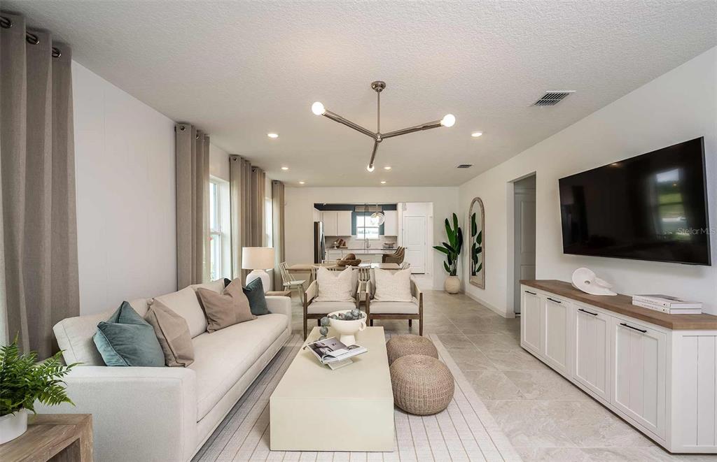A living room with a white sofa, coffee table, and television mounted above a cabinet — 9181 NEWMONS PLACE, WILDWOOD, FL