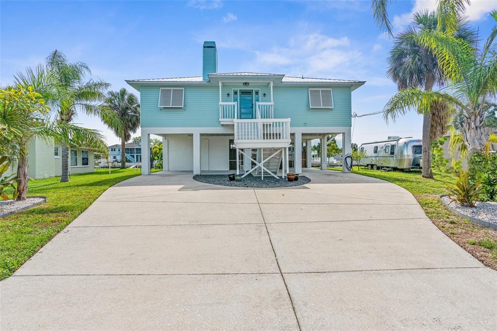 A light blue elevated house with a concrete driveway and a metal roof — 4464 JACONA DRIVE, HERNANDO BEACH, FL