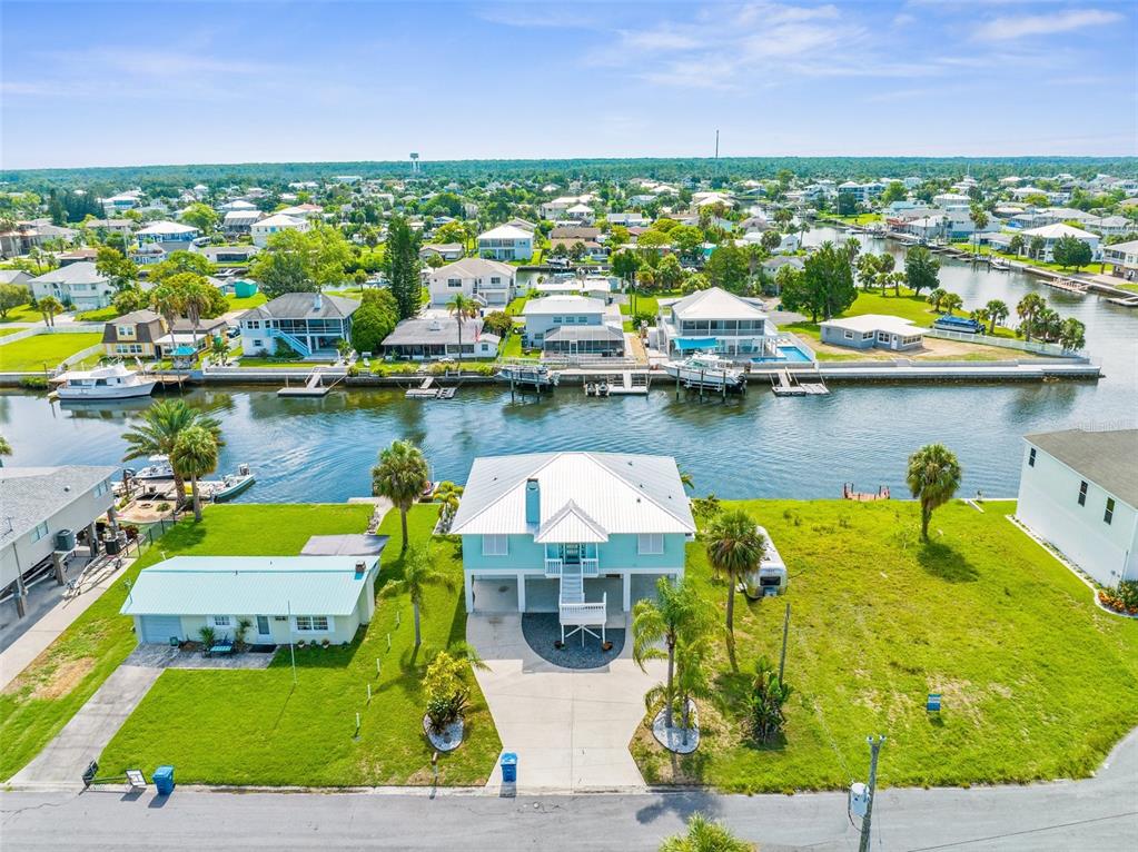 An aerial view shows a waterfront house with a metal roof and a detached garage — 4464 JACONA DRIVE, HERNANDO BEACH, FL