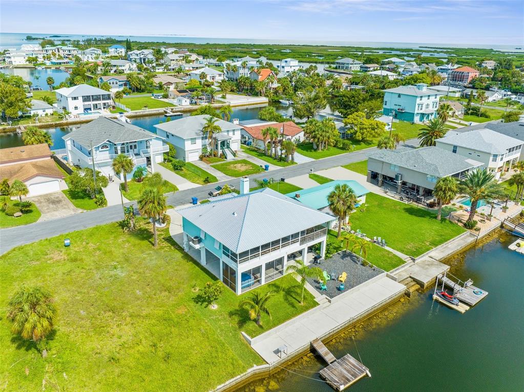 An aerial view shows a waterfront house with a metal roof and a private dock — 4464 JACONA DRIVE, HERNANDO BEACH, FL