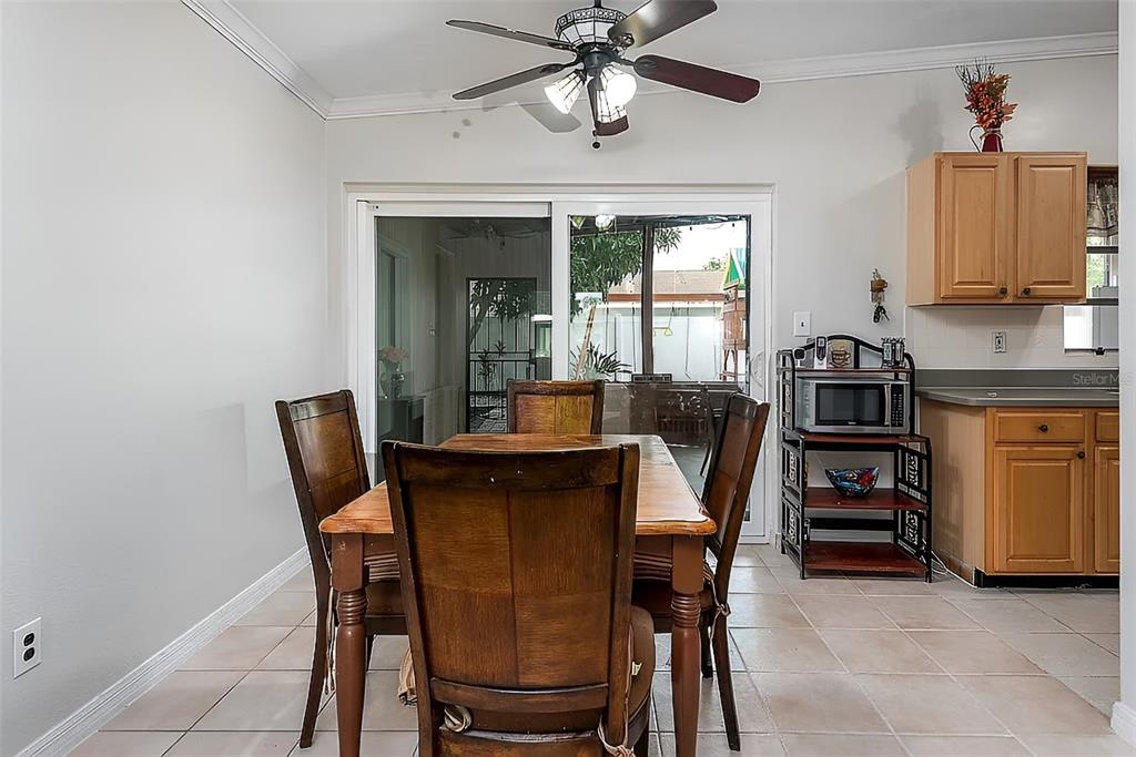 A dining area with a wooden table, four chairs, tile flooring, and a sliding glass door — 7008 TRIPOLI WAY, ORLANDO, FL