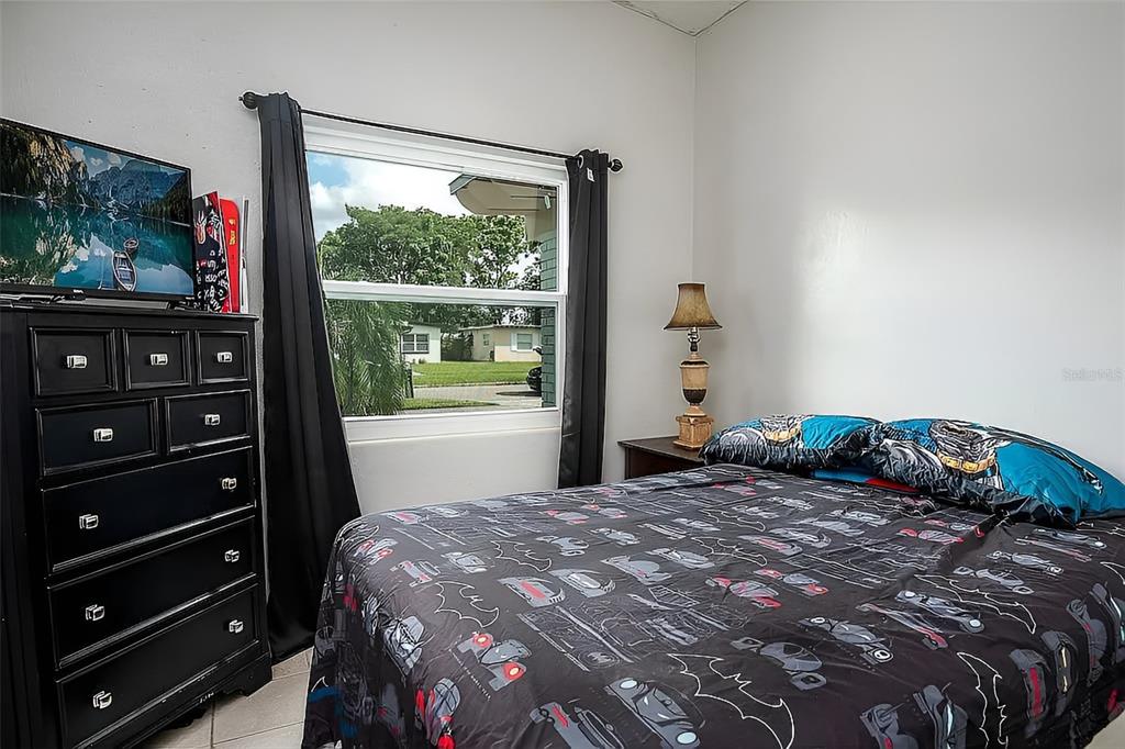 A bedroom features a black dresser, a window with dark curtains, and a Batman-themed bed — 7008 TRIPOLI WAY, ORLANDO, FL