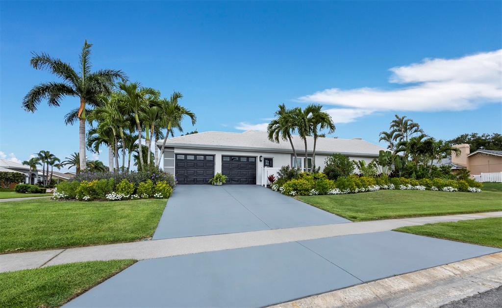 A single-story house with a two-car garage, gray driveway, and palm trees in the yard — 206 FOUR KNOT LANE, OSPREY, FL