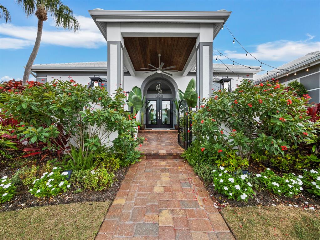 A brick walkway leads to the covered entryway of a modern home with lush landscaping — 206 FOUR KNOT LANE, OSPREY, FL