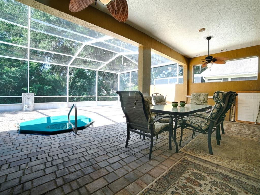 A covered patio features a brick floor, a dining set, and an enclosed swimming pool — 830 OLD OAKS LANE, LEESBURG, FL