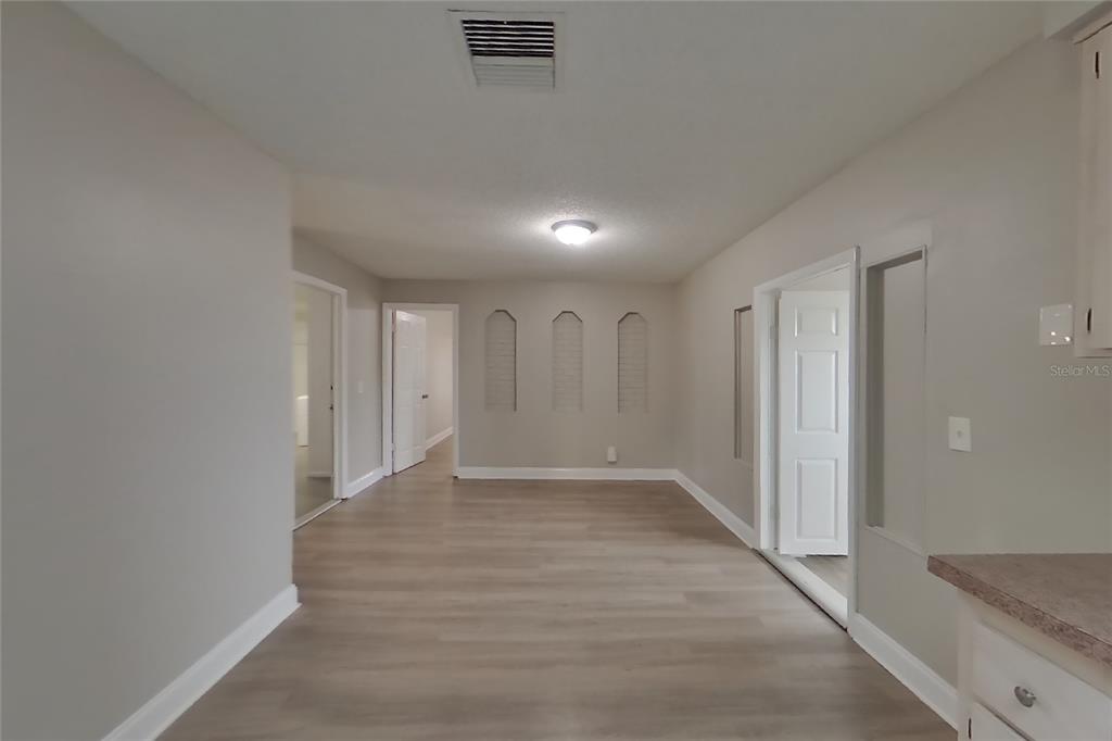 A room with light-colored walls, wood-look flooring, three arched wall niches, and multiple doorways — 4905 LEPRECHAUN WAY, ORLANDO, FL