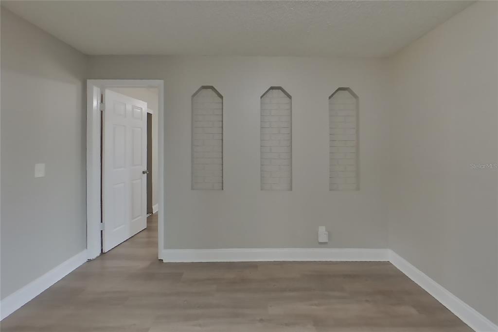 A room with light gray walls, wood-look flooring, and three arched wall niches — 4905 LEPRECHAUN WAY, ORLANDO, FL