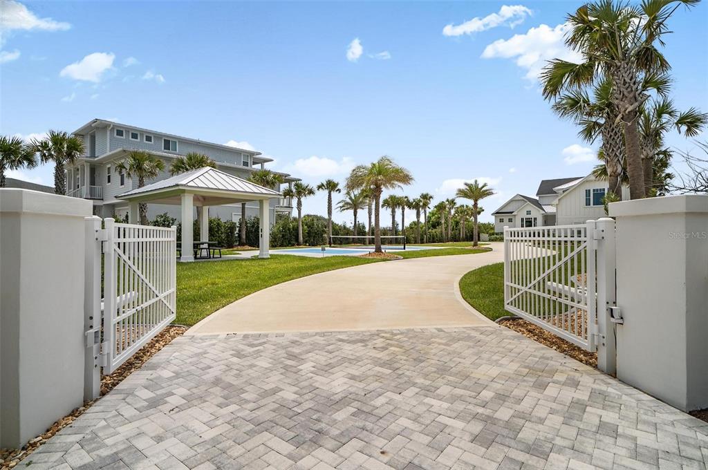 A paved driveway leads through an open gate toward a gazebo and swimming pool area — 8065 A1A S, ST AUGUSTINE, FL
