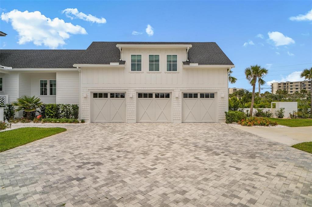 A three-car garage with white siding and a paved driveway under a blue sky — 8065 A1A S, ST AUGUSTINE, FL