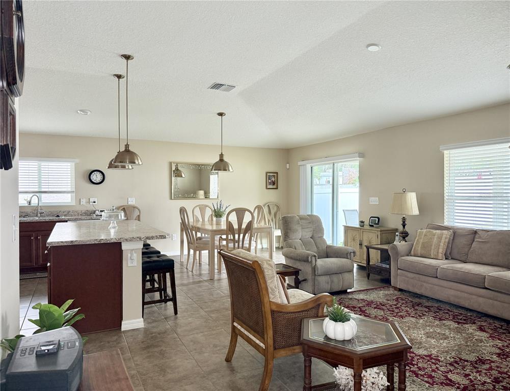 An open-concept living and dining area features a kitchen island, tile flooring, and neutral walls — 9242 FREEDOM HILL DR, SEFFNER, FL