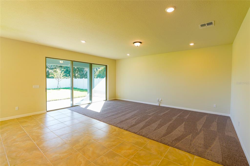A living room features a tiled floor area, carpeted section, and sliding glass doors to outside — 2779 MATERA DRIVE, ST CLOUD, FL