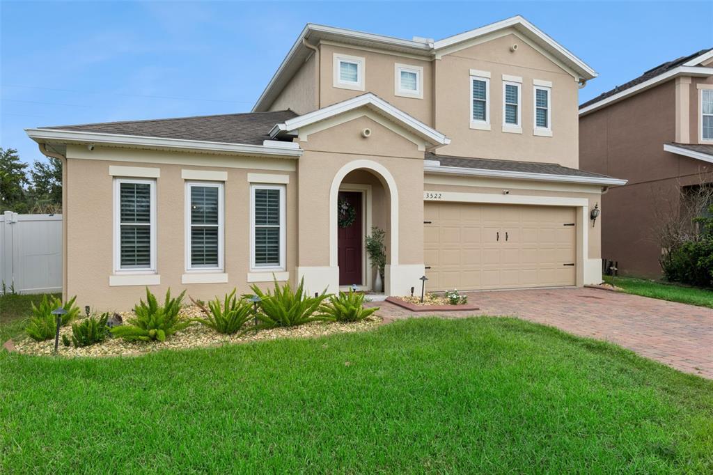 A two-story suburban house with a tan stucco exterior, a garage, and a front lawn — 3522 HEART PINE LOOP, OCOEE, FL