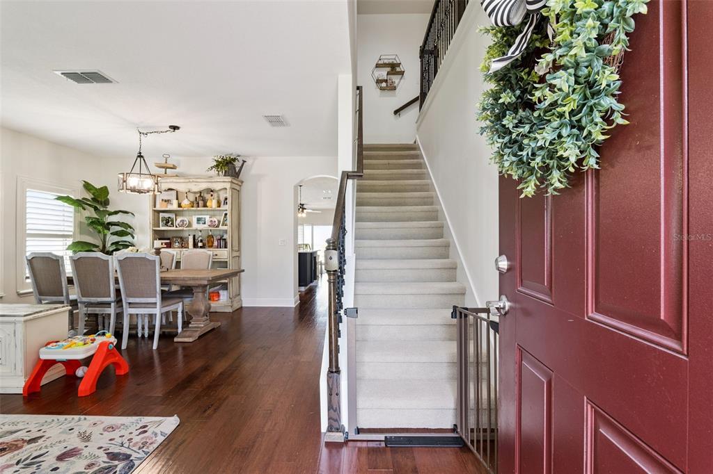An entryway features a red front door, a carpeted staircase, and a dining area nearby — 3522 HEART PINE LOOP, OCOEE, FL