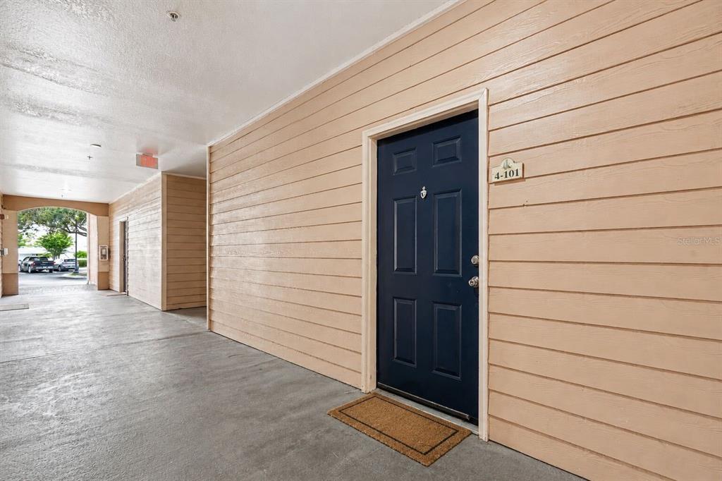 A dark blue front door with a unit number sign is set in a beige-sided wall — 5000 CULBREATH KEY WAY UNIT 4-101, TAMPA, FL