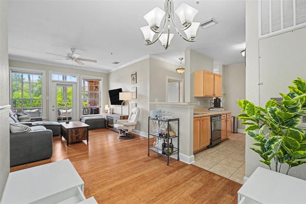 A living room with wood flooring flows into a kitchen with light wood cabinets — 5000 CULBREATH KEY WAY UNIT 4-101, TAMPA, FL