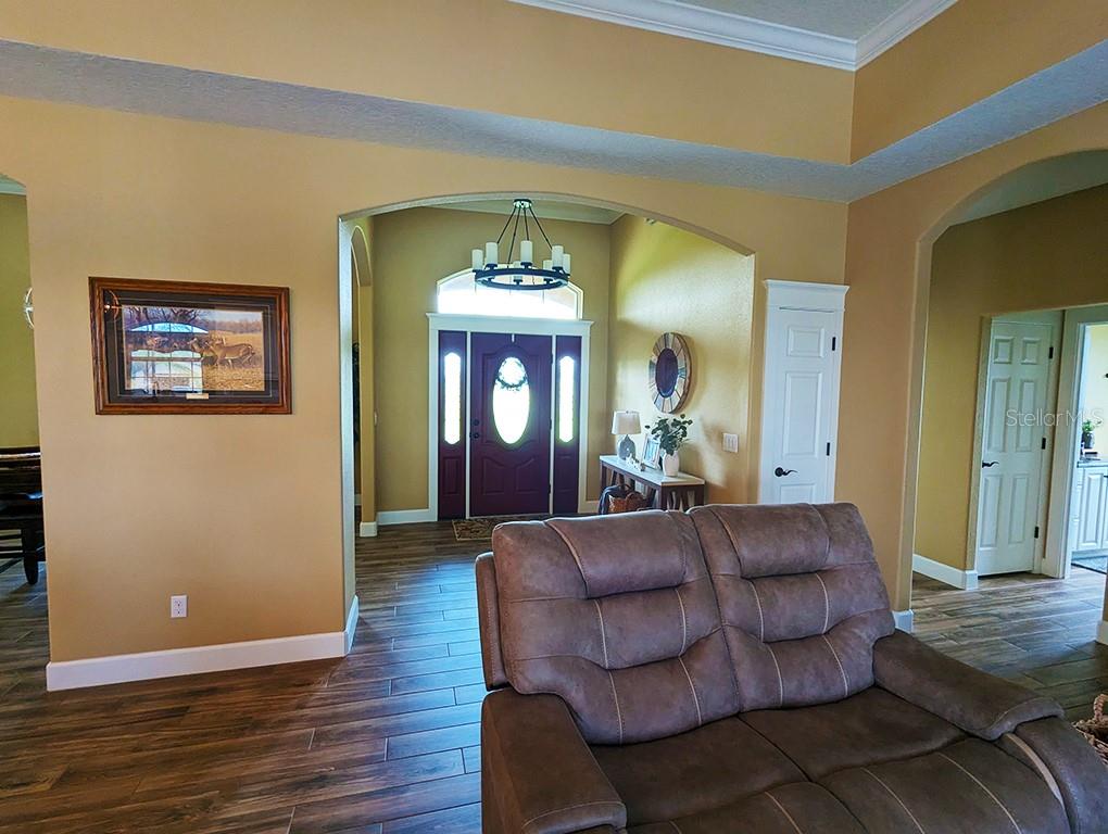 A living room with wood-look tile flooring features a view toward a purple front door — 19221 BAKER ROAD, UMATILLA, FL