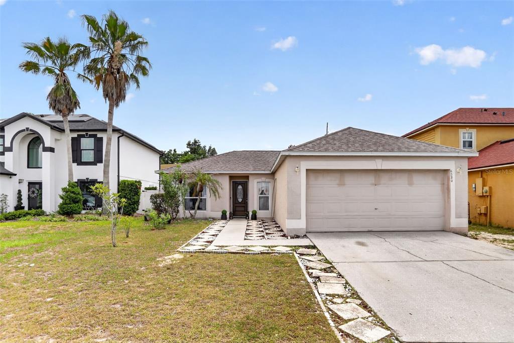 A single-story house with a beige stucco exterior, a two-car garage, and a palm tree — 6820 POMEROY CIRCLE, ORLANDO, FL