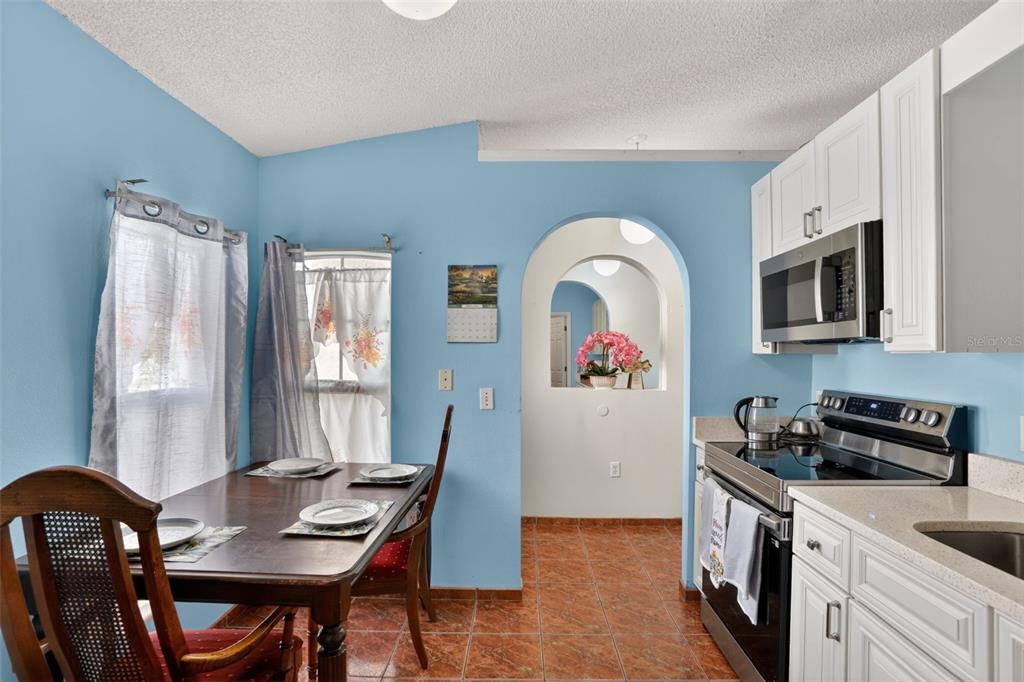 A kitchen and dining area with blue walls, white cabinets, and tiled flooring — 6820 POMEROY CIRCLE, ORLANDO, FL
