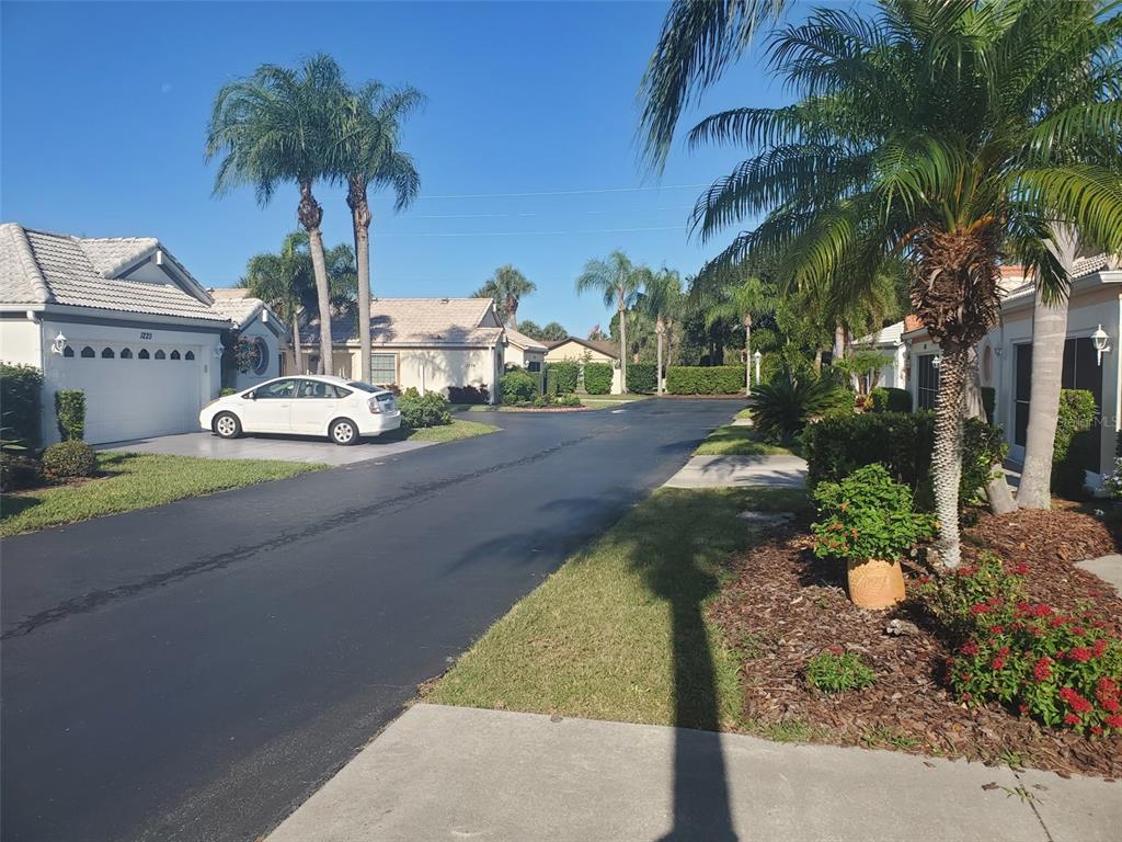 A white car is parked in the driveway of a house on a suburban street — 1232 CAPRI ISLES BOULEVARD UNIT 48, VENICE, FL