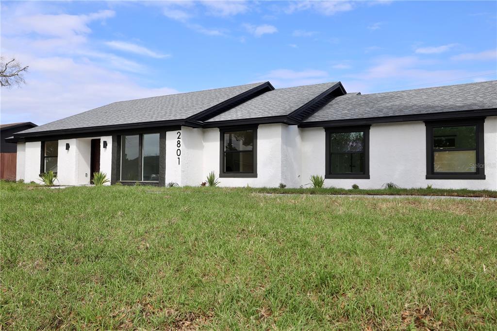 A white house with a black roof and a detached garage features a paved driveway — 2801 WAUMPI TRAIL, MAITLAND, FL