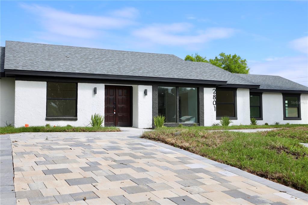 A single-story house with a white stucco exterior, dark trim, and a paved driveway — 2801 WAUMPI TRAIL, MAITLAND, FL