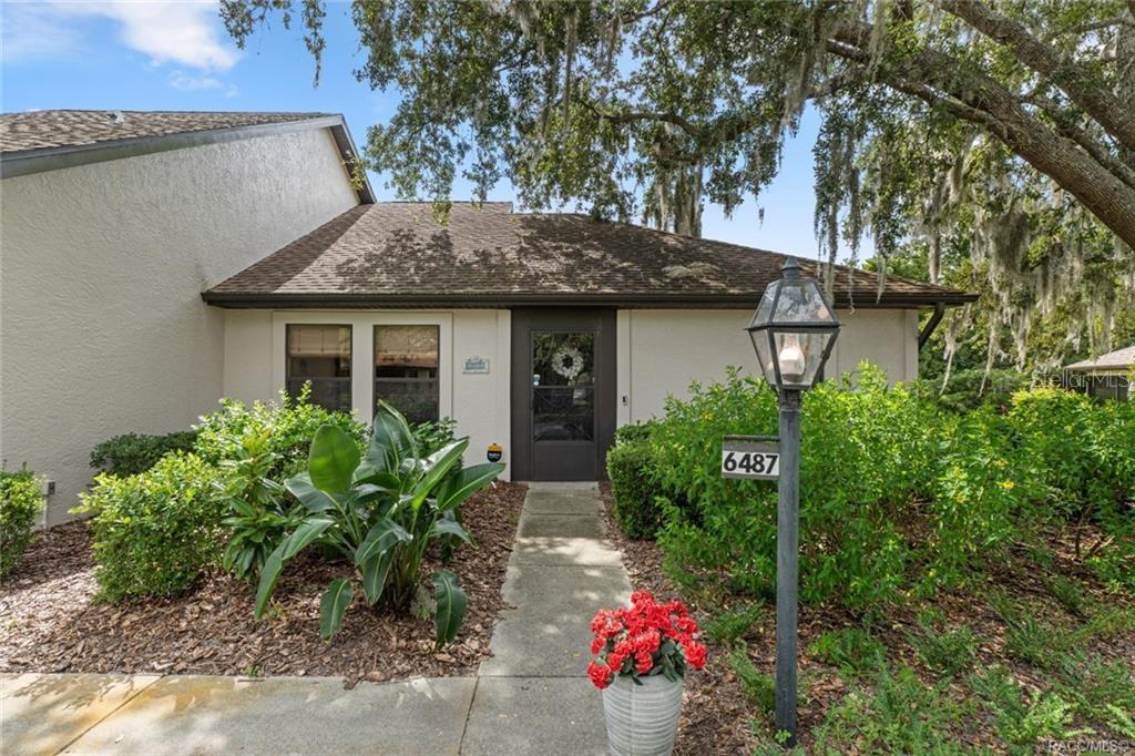 A single-story house exterior features a concrete walkway leading to a front door with landscaping — 6487 W LEXINGTON DRIVE, CRYSTAL RIVER, FL