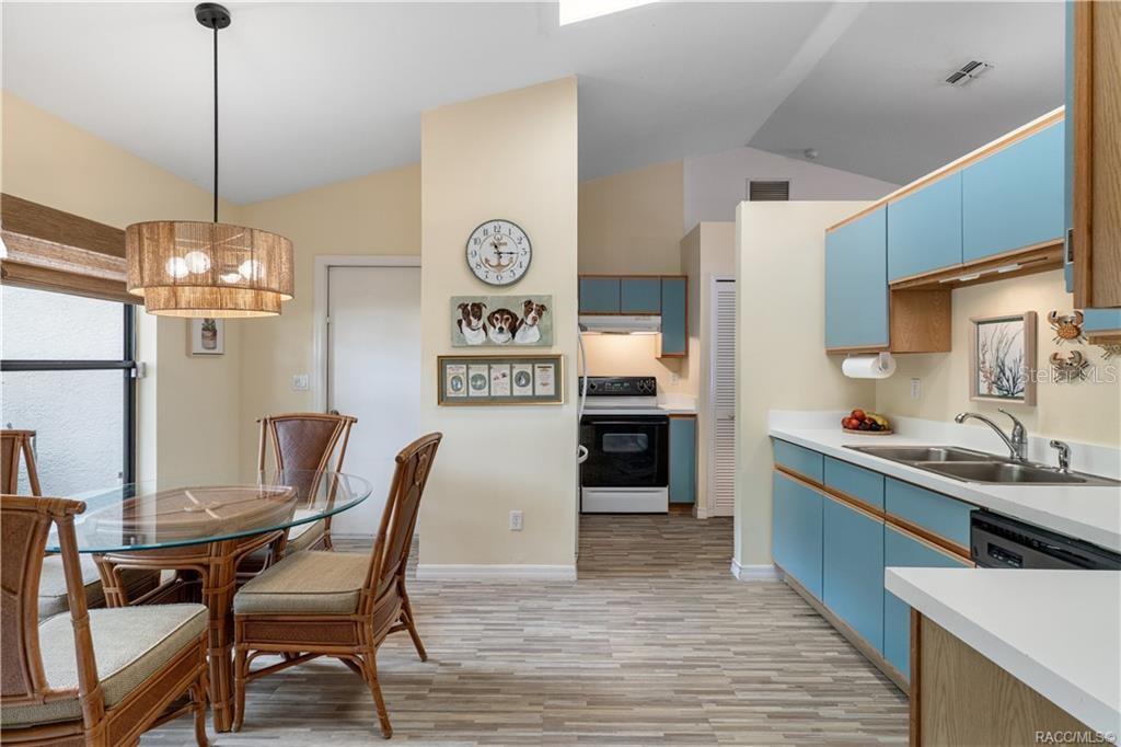 A kitchen and dining area with blue cabinets, light walls, and a glass-topped rattan table — 6487 W LEXINGTON DRIVE, CRYSTAL RIVER, FL