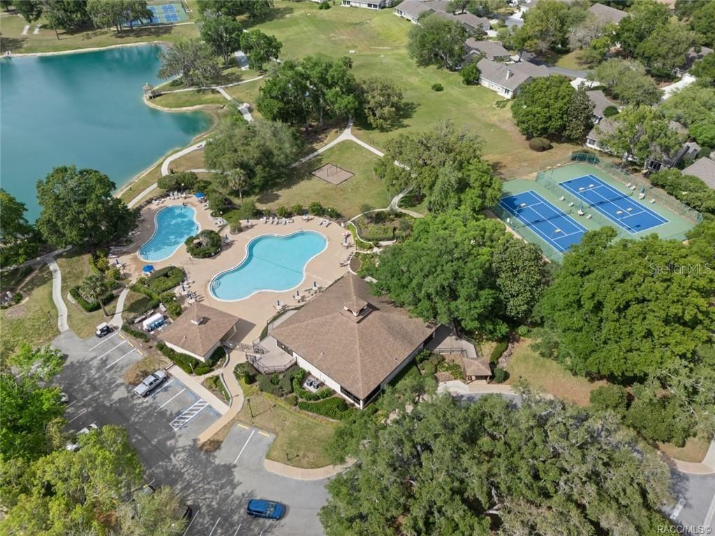 An aerial view shows a community clubhouse with swimming pools, tennis courts, and a lake — 6487 W LEXINGTON DRIVE, CRYSTAL RIVER, FL