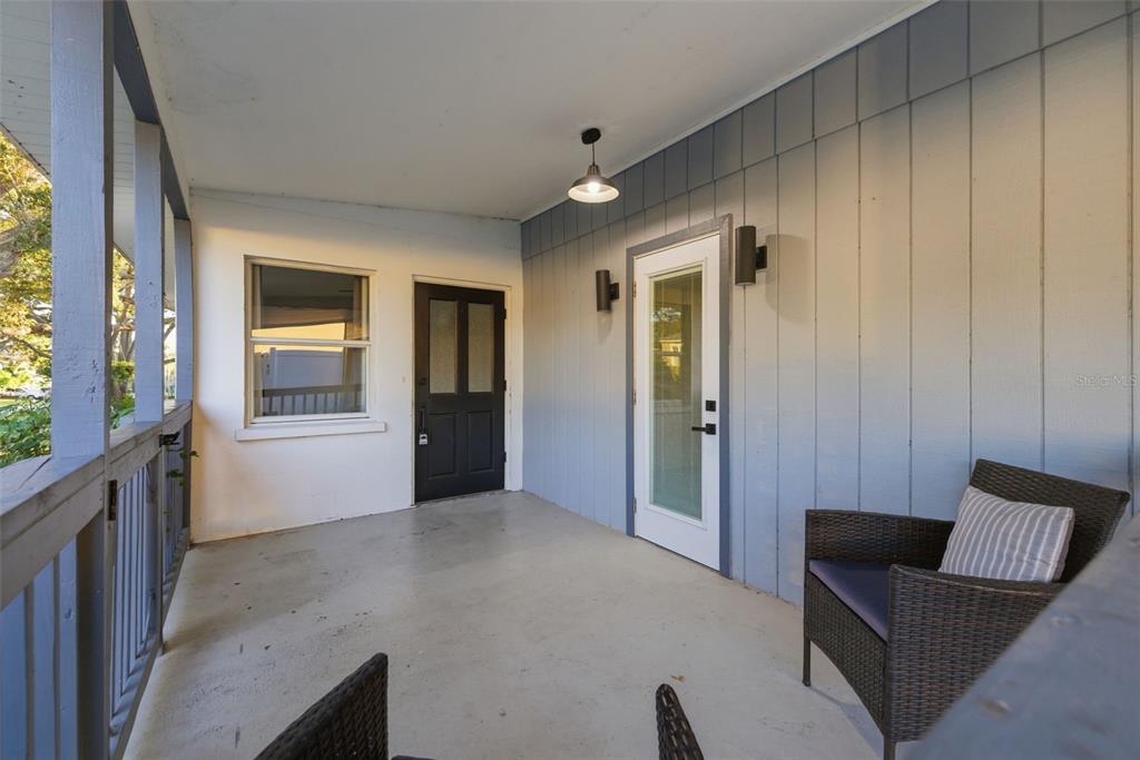 A covered porch features a concrete floor, a wicker chair, and two exterior doors — 7198 121ST WAY, SEMINOLE, FL