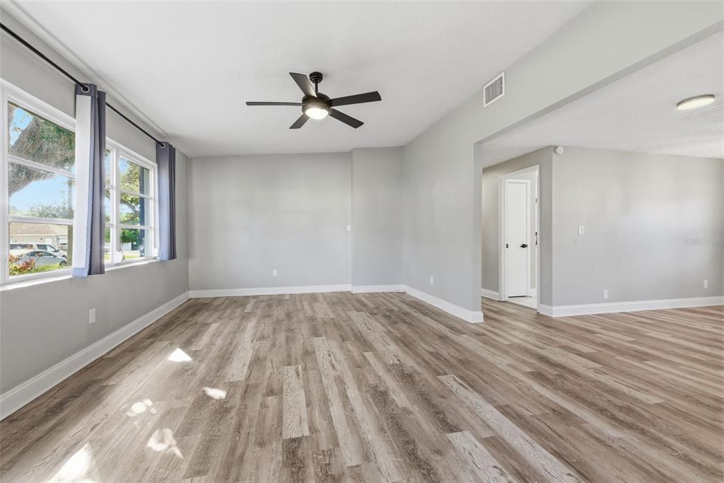 An empty living room features light gray walls, wood-look flooring, and a ceiling fan — 7198 121ST WAY, SEMINOLE, FL