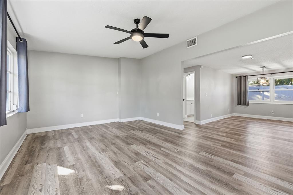 An open living area features light gray walls, wood-look flooring, and a black ceiling fan — 7198 121ST WAY, SEMINOLE, FL