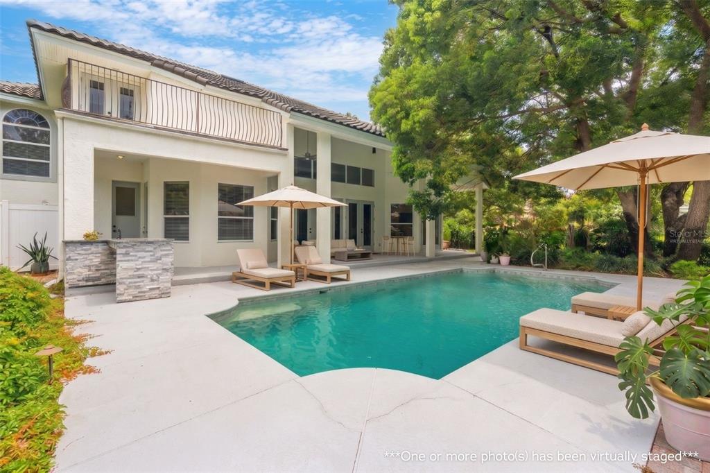 A backyard swimming pool with lounge chairs and an umbrella next to a two-story house — 2540 HEMPEL COVE CT, WINDERMERE, FL