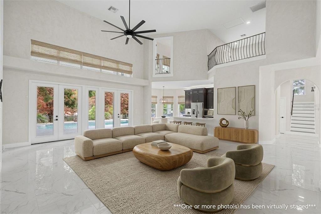 A spacious living room with high ceilings, marble floors, a large sectional, and pool views — 2540 HEMPEL COVE CT, WINDERMERE, FL