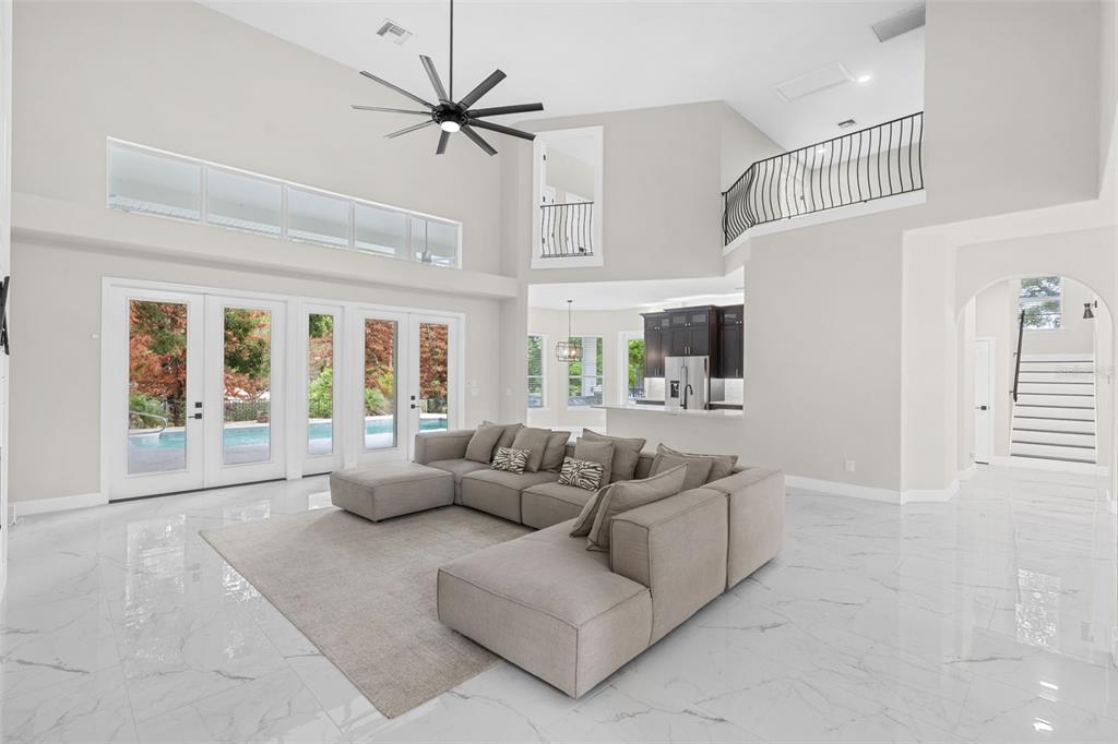 A spacious living room with marble floors, a large sectional sofa, and a high ceiling — 2540 HEMPEL COVE CT, WINDERMERE, FL