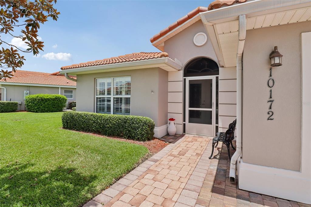 A paved walkway leads to the front entrance of a house with a tiled roof — 10172 MAINSAIL DRIVE, OXFORD, FL