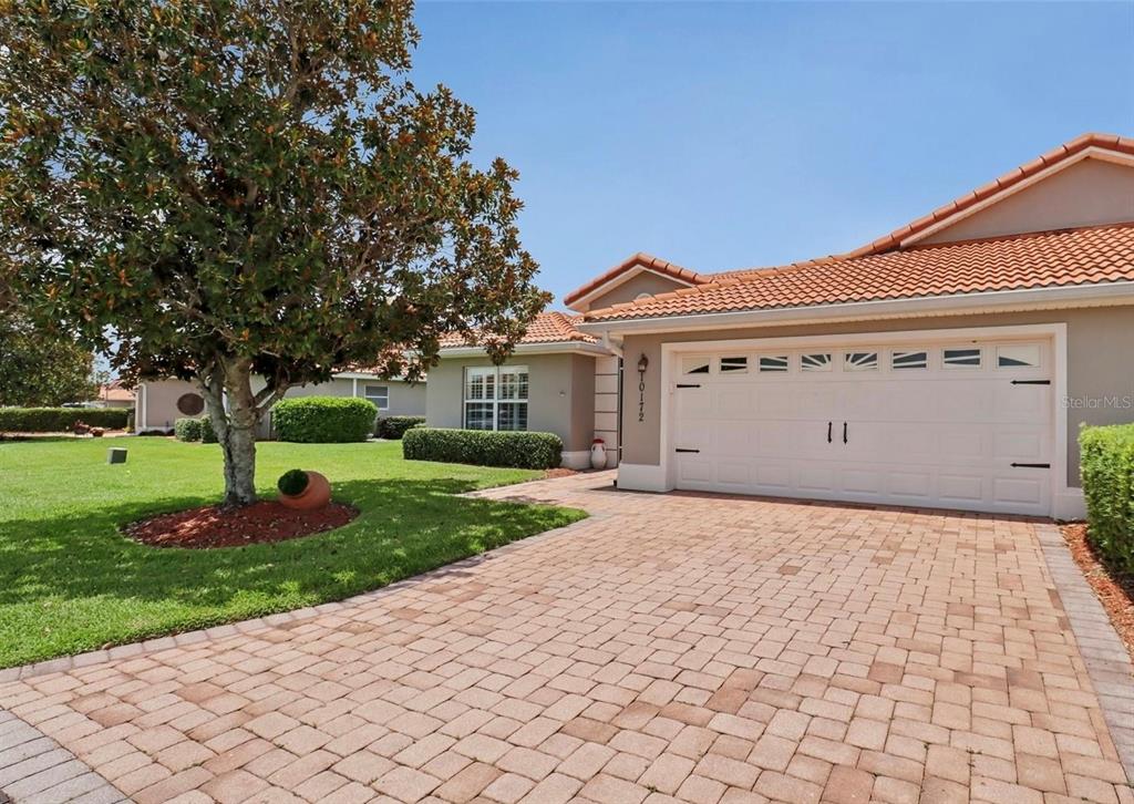 A single-story house with a tiled roof, a two-car garage, and a brick paver driveway — 10172 MAINSAIL DRIVE, OXFORD, FL
