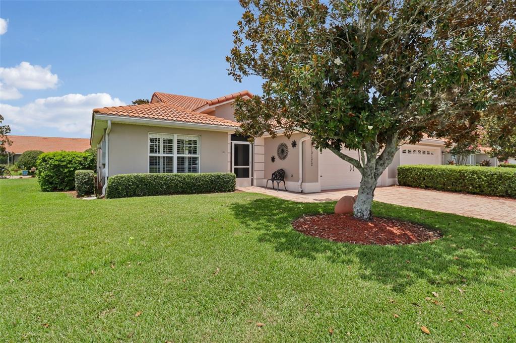 A single-story house with a tile roof, brick driveway, and a large tree in front — 10172 MAINSAIL DRIVE, OXFORD, FL