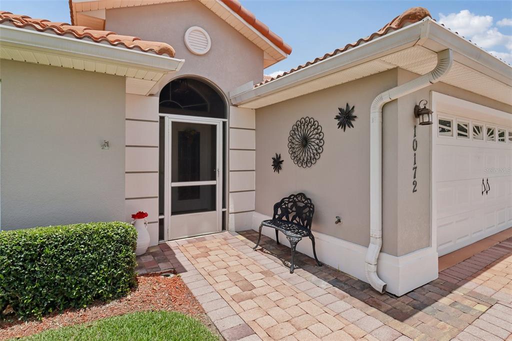 The exterior of a house features a paved walkway, a metal bench, and a garage — 10172 MAINSAIL DRIVE, OXFORD, FL