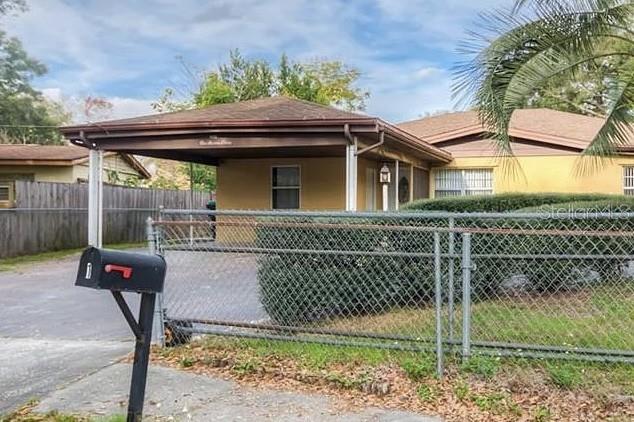 A single-story house with a carport and a chain-link fence in the front yard — 1 S AURORA DRIVE, APOPKA, FL