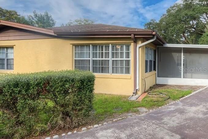 A yellow house with a screened-in porch and a large hedge in the front yard — 1 S AURORA DRIVE, APOPKA, FL