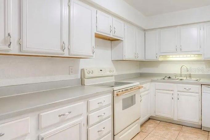 A kitchen features white cabinets, light countertops, and a white electric range — 1 S AURORA DRIVE, APOPKA, FL